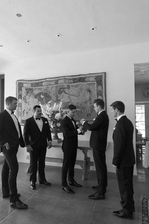 Formal gathering in an art gallery with people viewing displayed artwork on white walls.