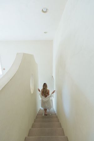 A minimalist white staircase with white walls leads upward in a bright interior space.