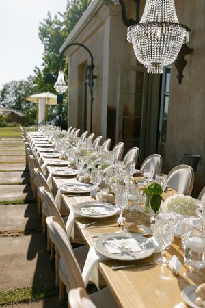 An elegant outdoor wedding reception table setting with crystal chandeliers and white place settings along a terrace.

Auberge du Soleil Wed