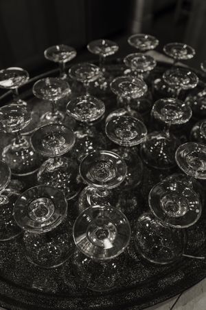 Rows of empty champagne coupes arranged on a dark surface in black and white.