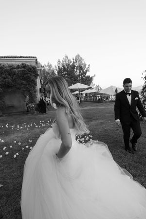 Wedding scene with flowing white dress and candles scattered on grass.
