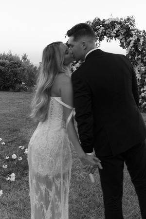 Couple walking through a garden setting in formal wedding attire.
