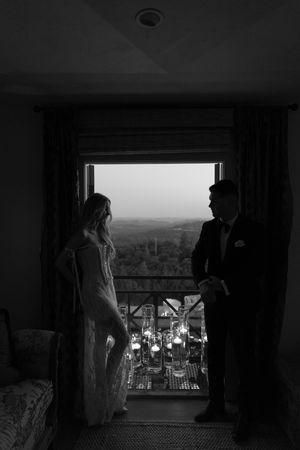 Silhouetted figures stand by a window overlooking a cityscape in a series of dramatic black and white shots.
