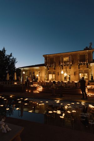Evening view of an elegant venue lit by candlelight and outdoor lighting fixtures.