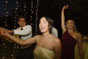Wedding guests dancing and celebrating at an evening reception with festive lighting.