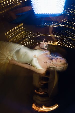 Long exposure wedding photo creates artistic light trails and motion blur effects around bride in white dress.