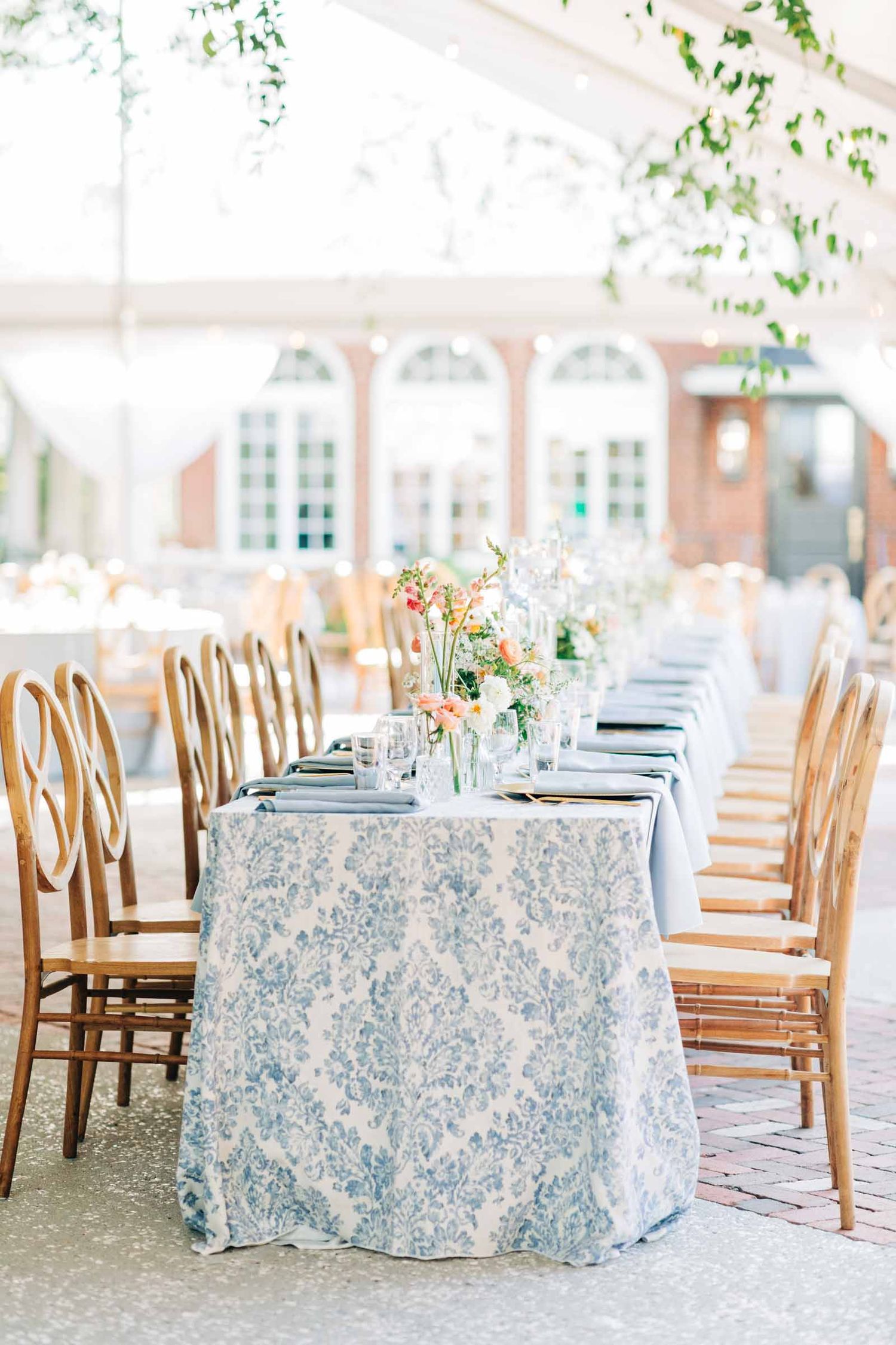 Elegant wedding reception table with blue damask tablecloth and gold chairs set under white tent with floral centerpieces 255 Milledge