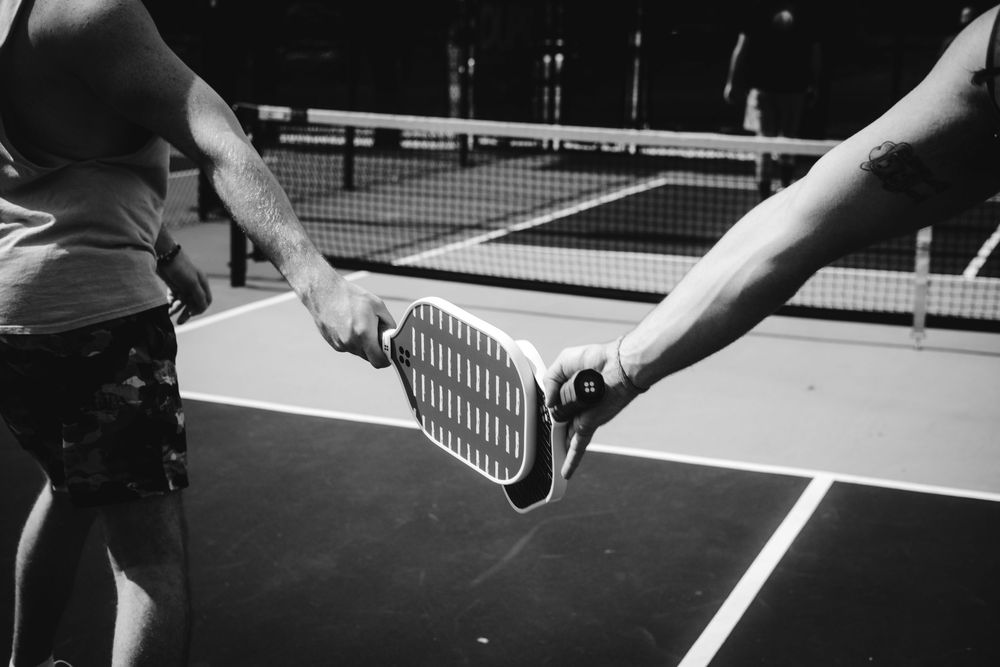 Two people playing tennis on a court, showing their hands holding rackets in a series of action shots.