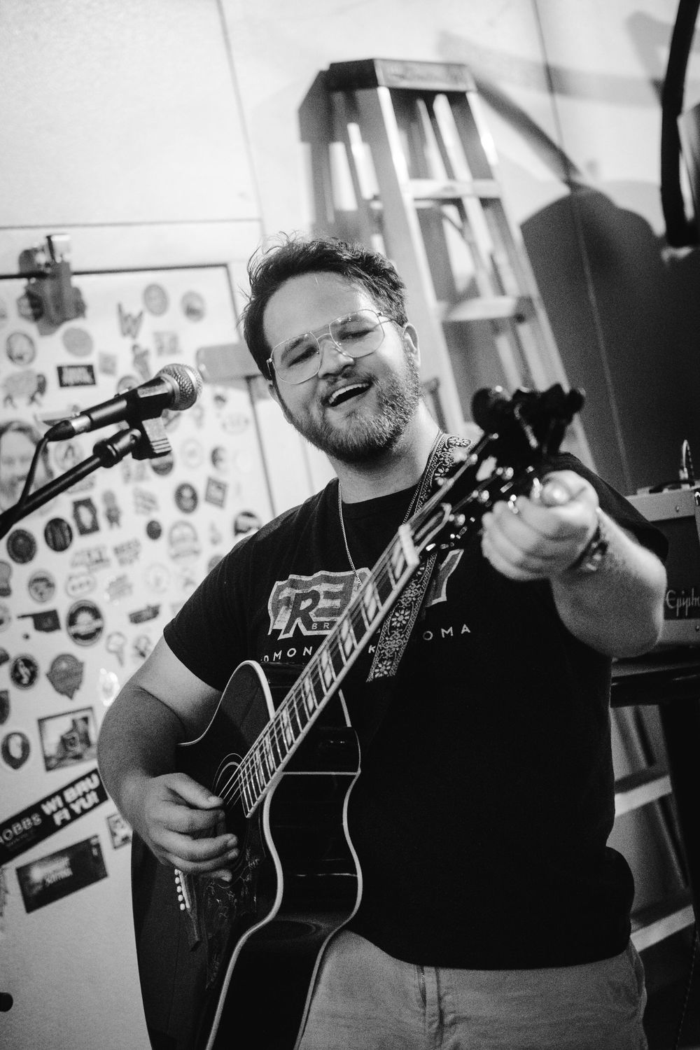 Black and white photos of a musician playing acoustic guitar in a casual indoor setting.