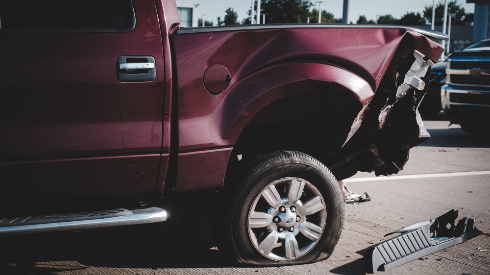 A maroon pickup truck is parked in a lot with multiple angles showing its side panels and wheels.