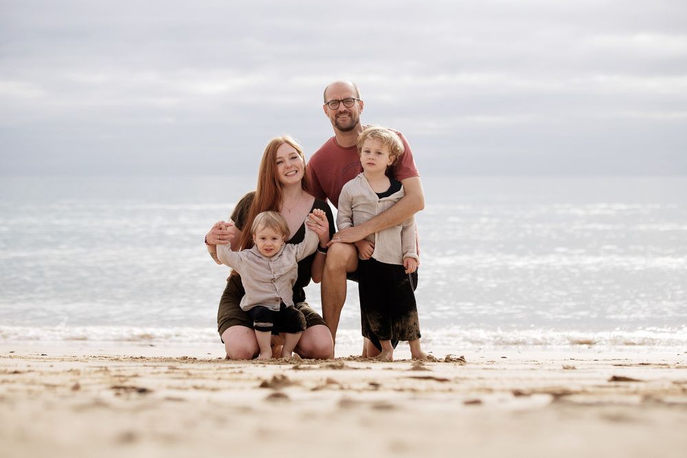A family of four posing together on the wide sands of Sotavento beach - Natural family photography in Fuerteventura
