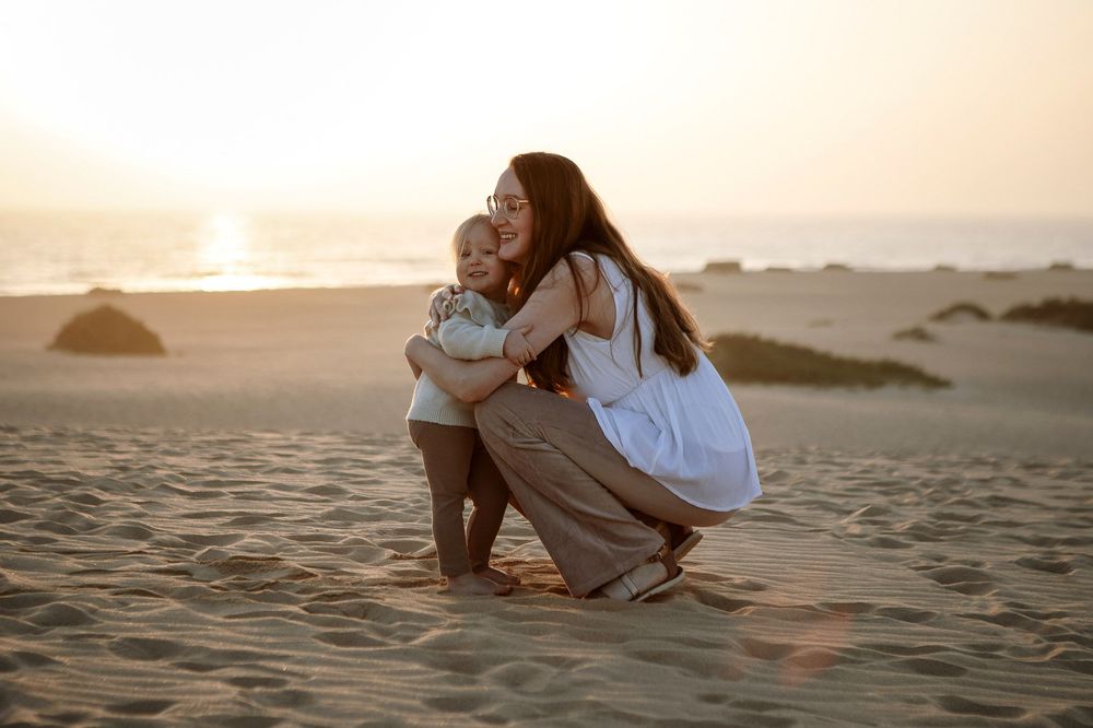 Mother and child sharing a quiet moment in the dunes at sunrise - Fuerteventura family photography
