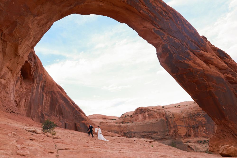 Panoramic view of natural sandstone arches and rock formations in a desert landscape at sunset.