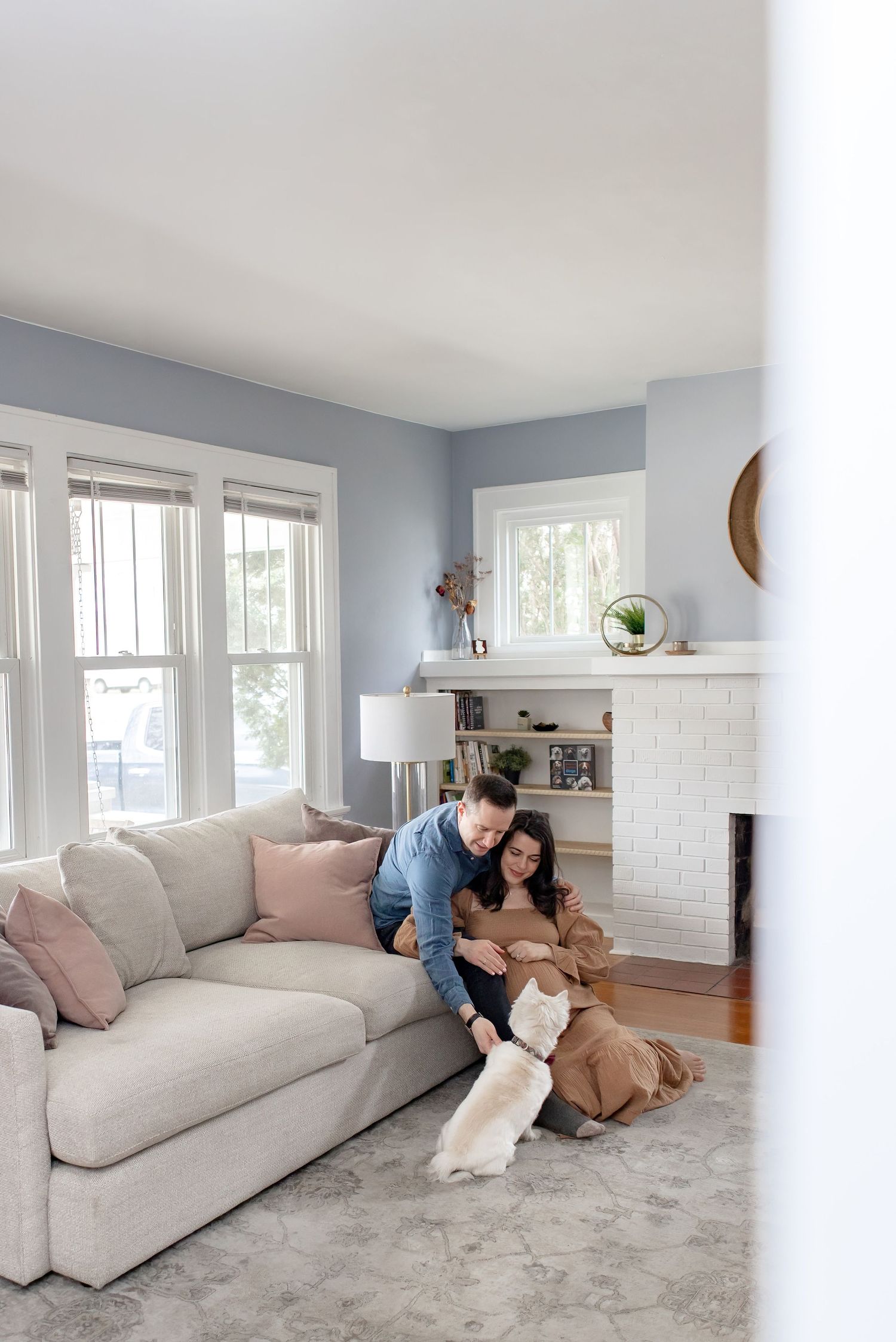 People relaxing on a light gray sectional sofa in a bright living room with soft blue walls and white trim.