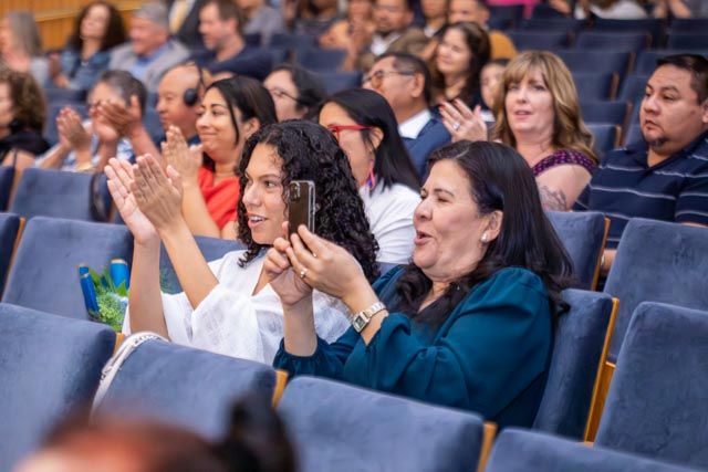 Diverse audience members react emotionally while watching an event in stadium seating.
