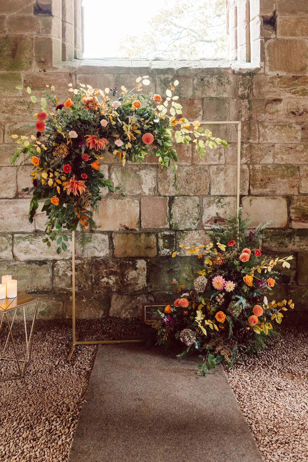 Colorful autumn floral arrangements with orange and yellow blooms decorate a rustic stone wall interior.