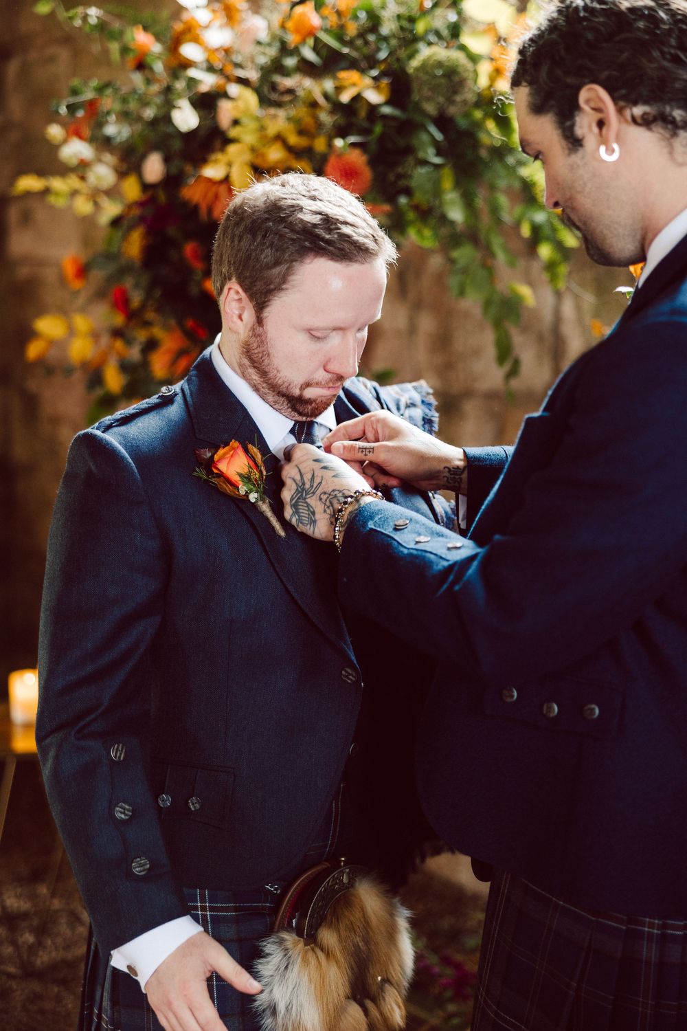 Emotional wedding moment captured under autumn foliage with navy blue attire.