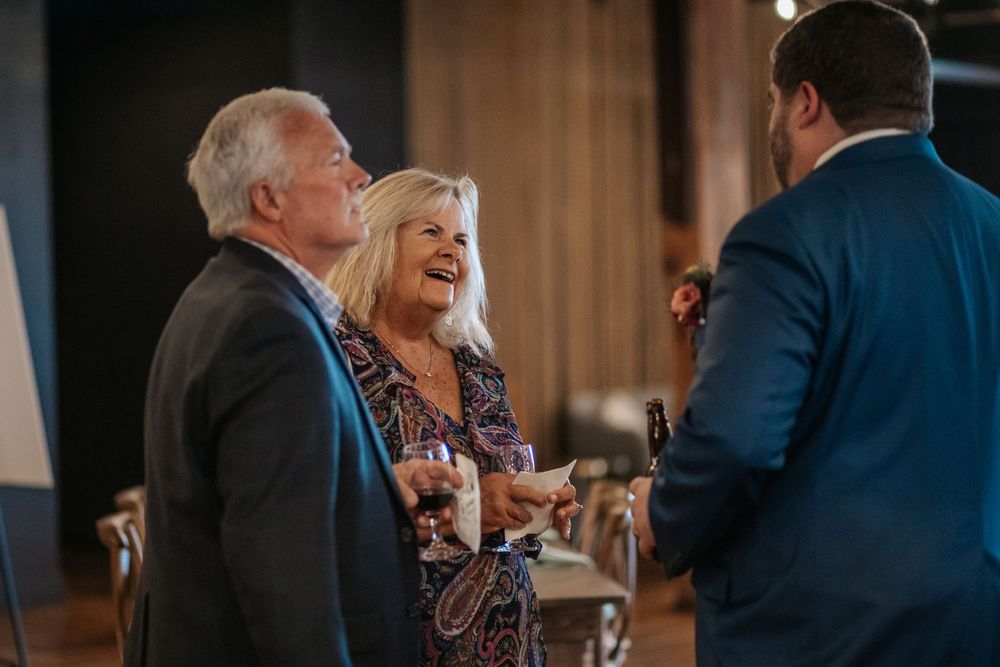 Wedding reception guests enjoying conversation at tables in a warmly lit indoor venue.