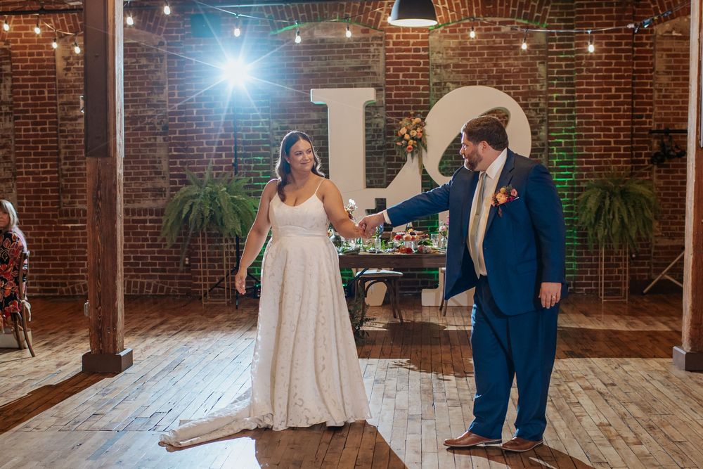 Wedding reception in an industrial brick venue with string lights and wooden floors.