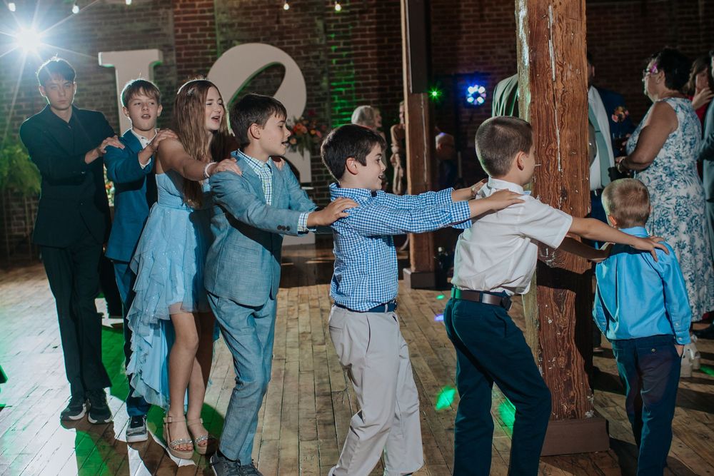 Wedding guests dancing and celebrating on the dance floor with colorful party lights.