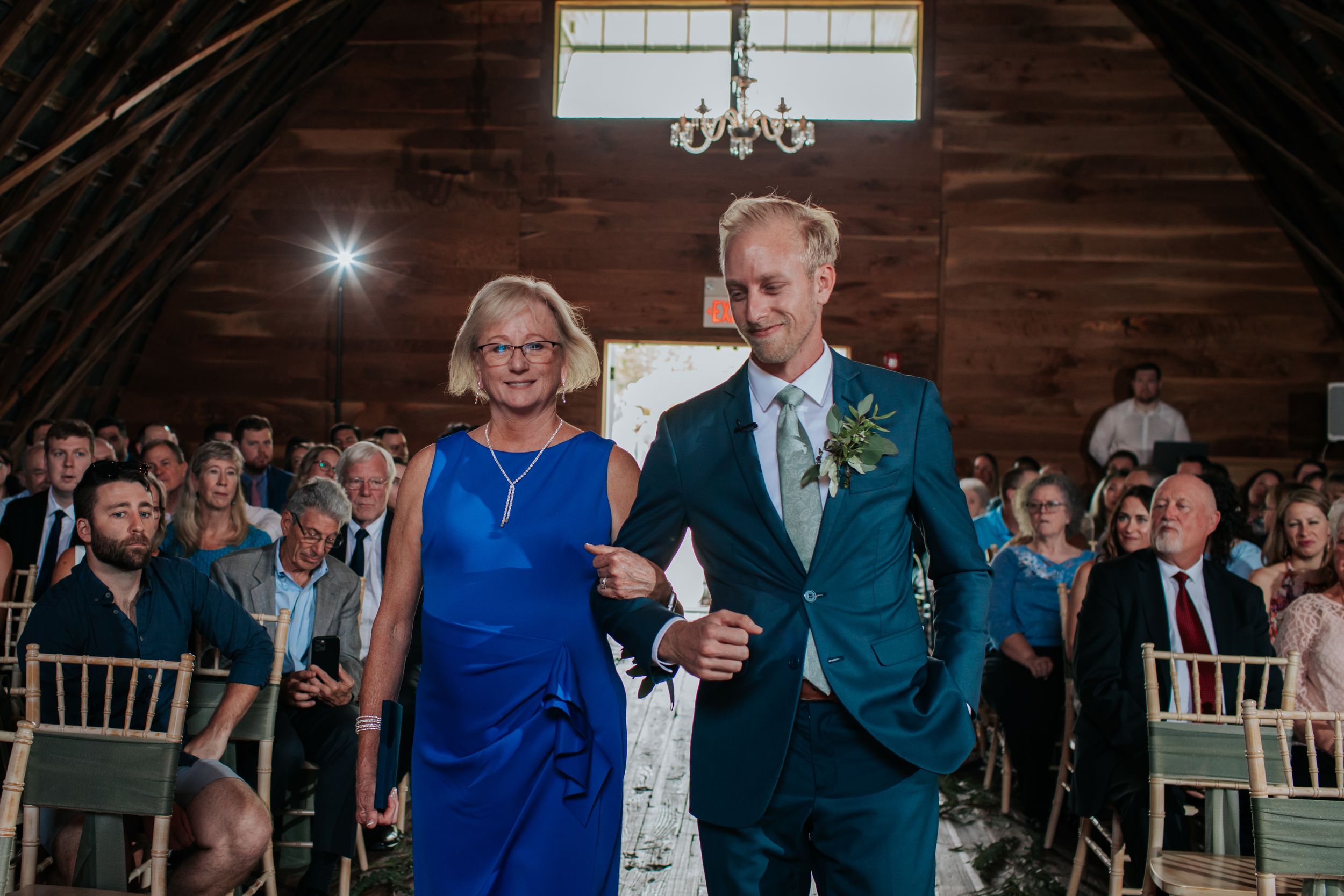Wedding celebration in a rustic barn venue with guests seated at round tables.