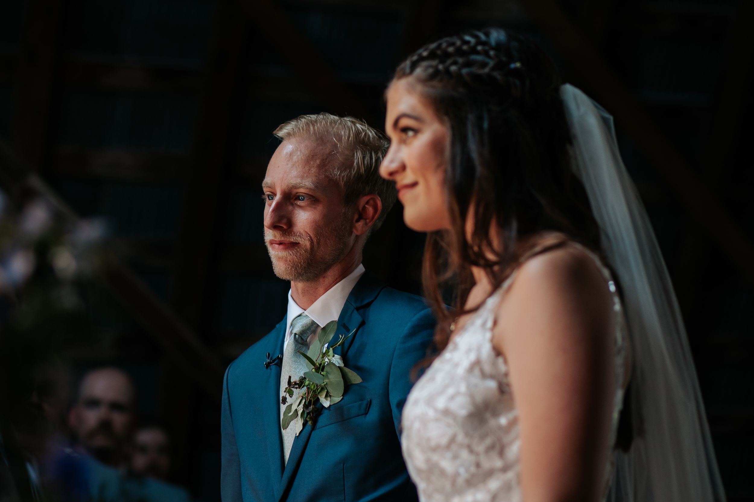 Intimate wedding ceremony moment captured in moody lighting with bridal veil visible.