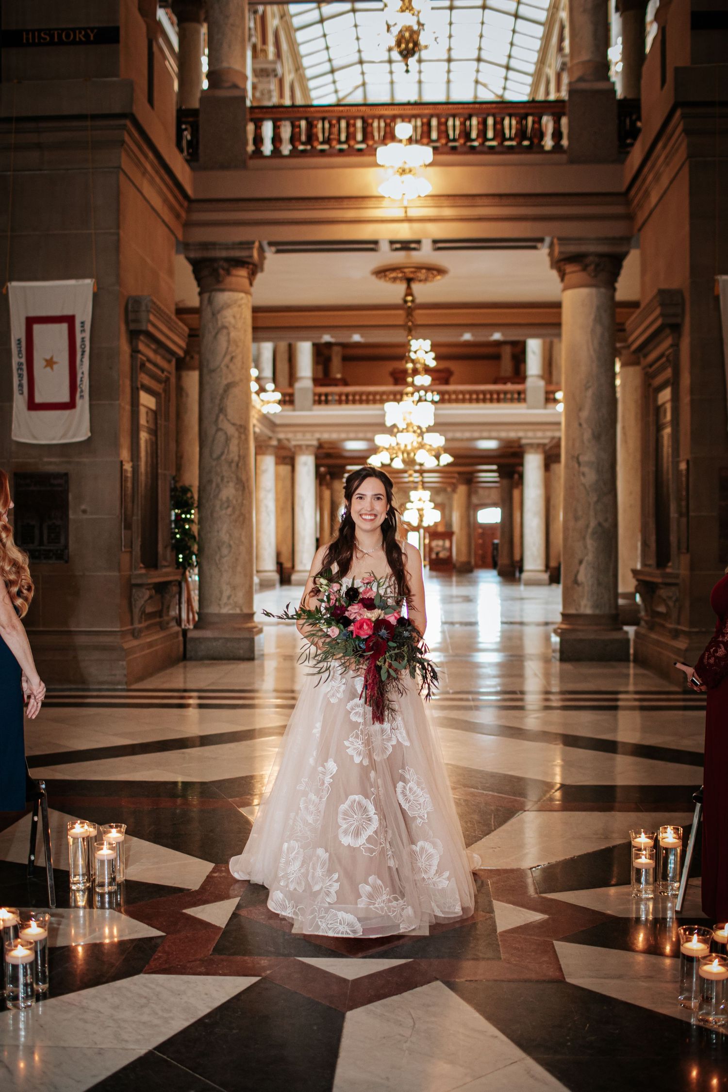 Elegant bridal portraits in a grand marble hallway with ornate chandeliers and classic architectural details.