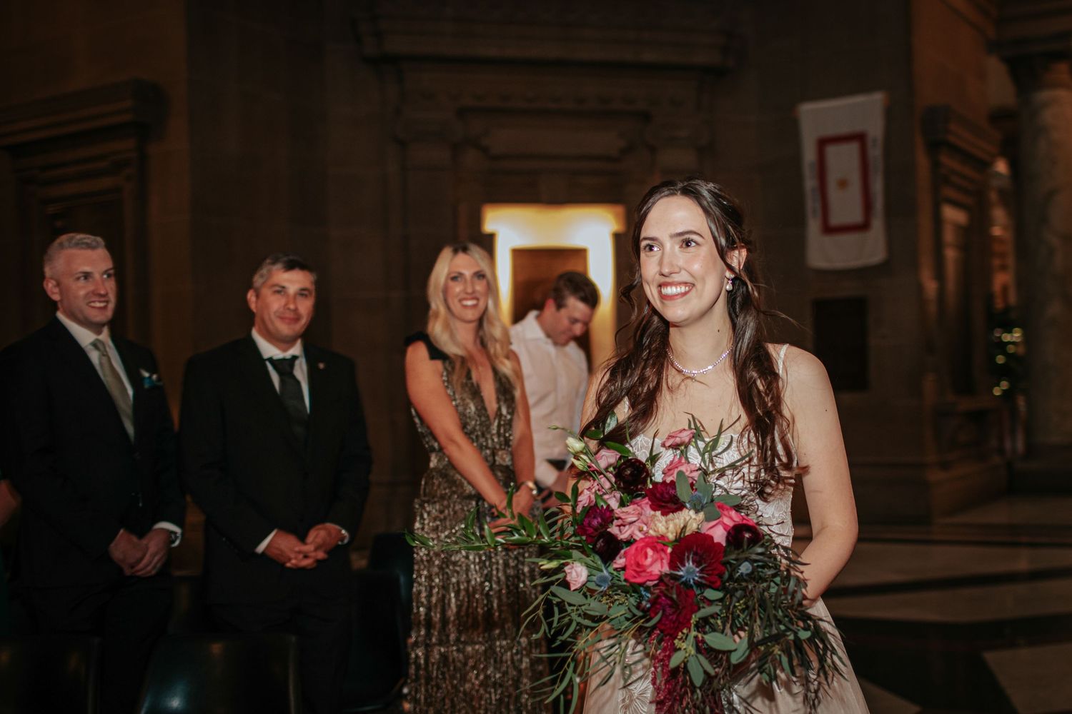 A wedding party celebrates during a reception in a rustic wooden lodge venue with warm lighting and floral decorations.