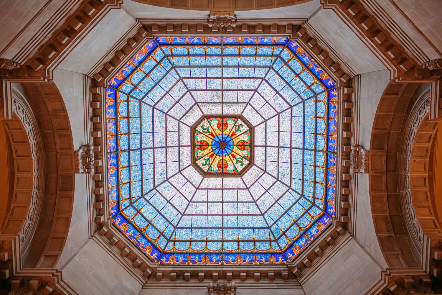 Ornate stained glass octagonal skylight ceiling with blue and gold geometric patterns.