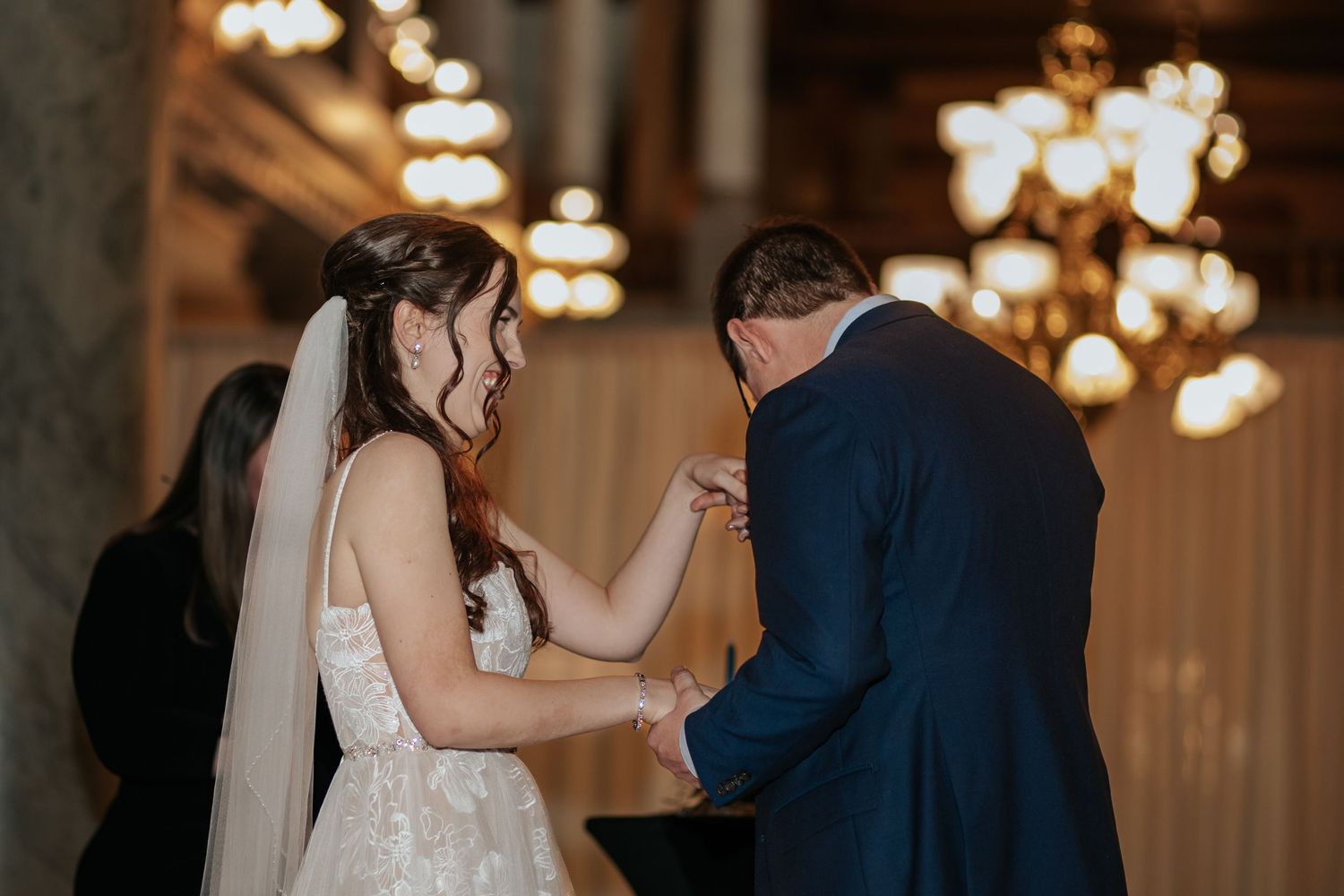 A tender moment during a wedding ceremony in an elegantly lit indoor venue.