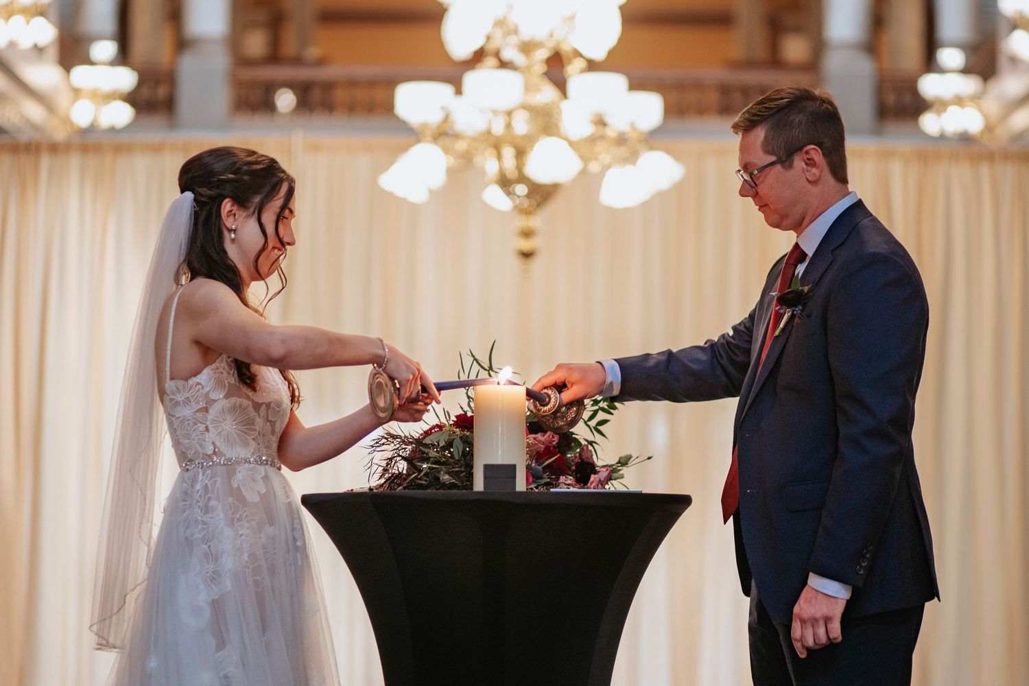 Wedding ceremony scene with candles and white draping in an elegant indoor venue.