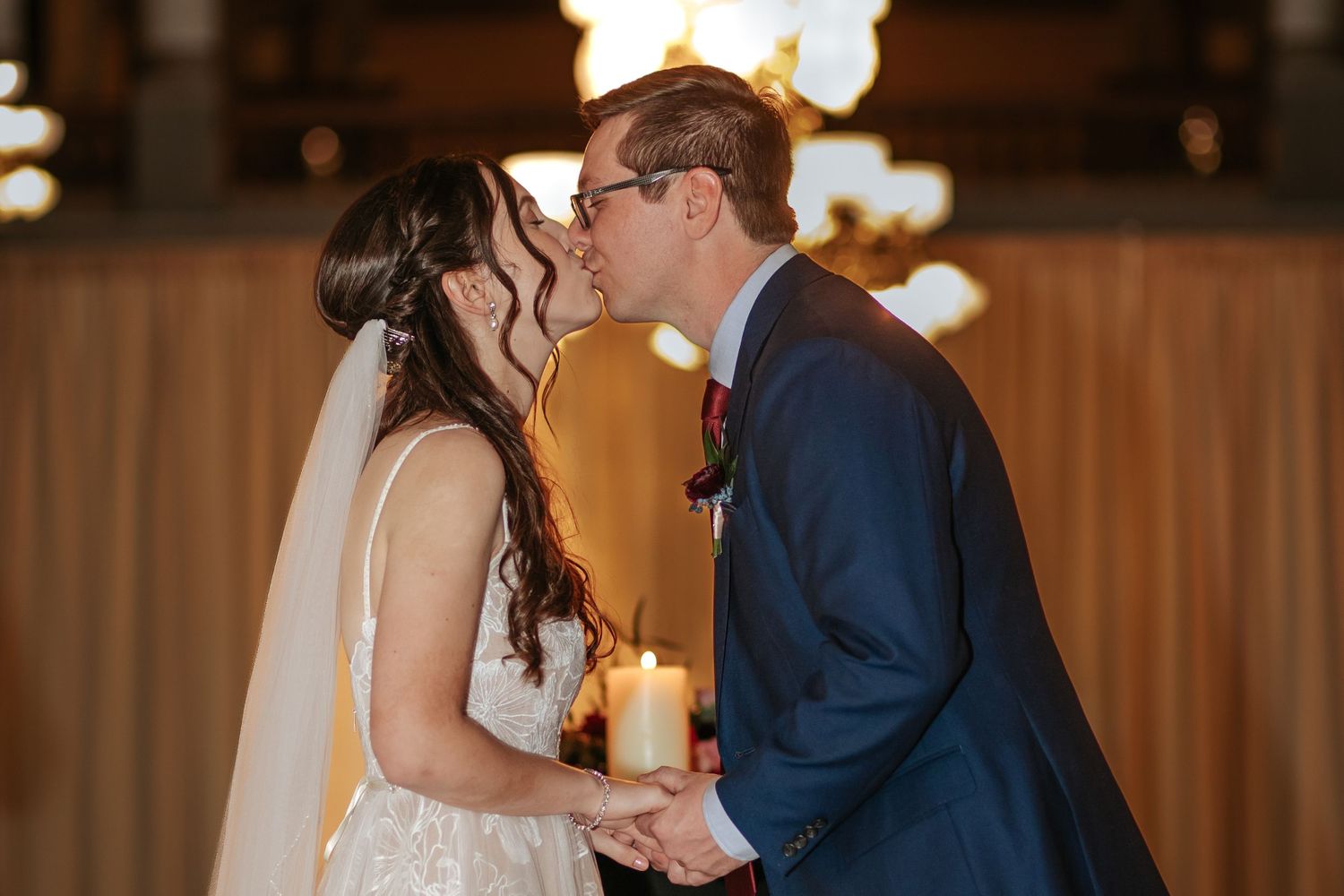 A couple shares an intimate moment during their first dance at an elegant candlelit wedding reception.