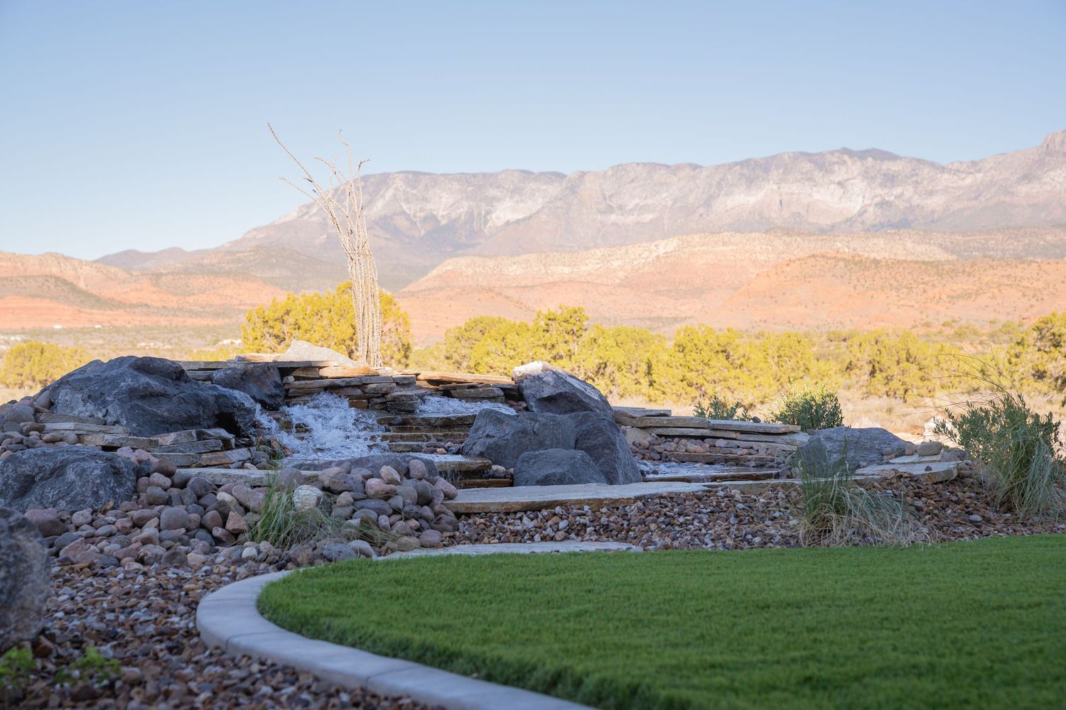 Curved pathway through landscaped garden with mountain backdrop in desert setting.