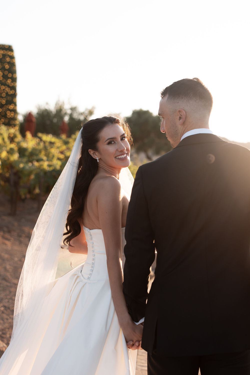A bride and groom share intimate moments during their sunset wedding photoshoot on a hilltop path.