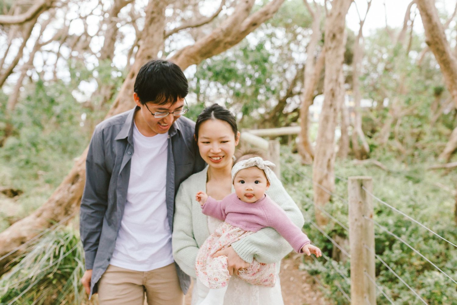 A joyful family moment captured in a natural outdoor setting with sunlight filtering through trees.