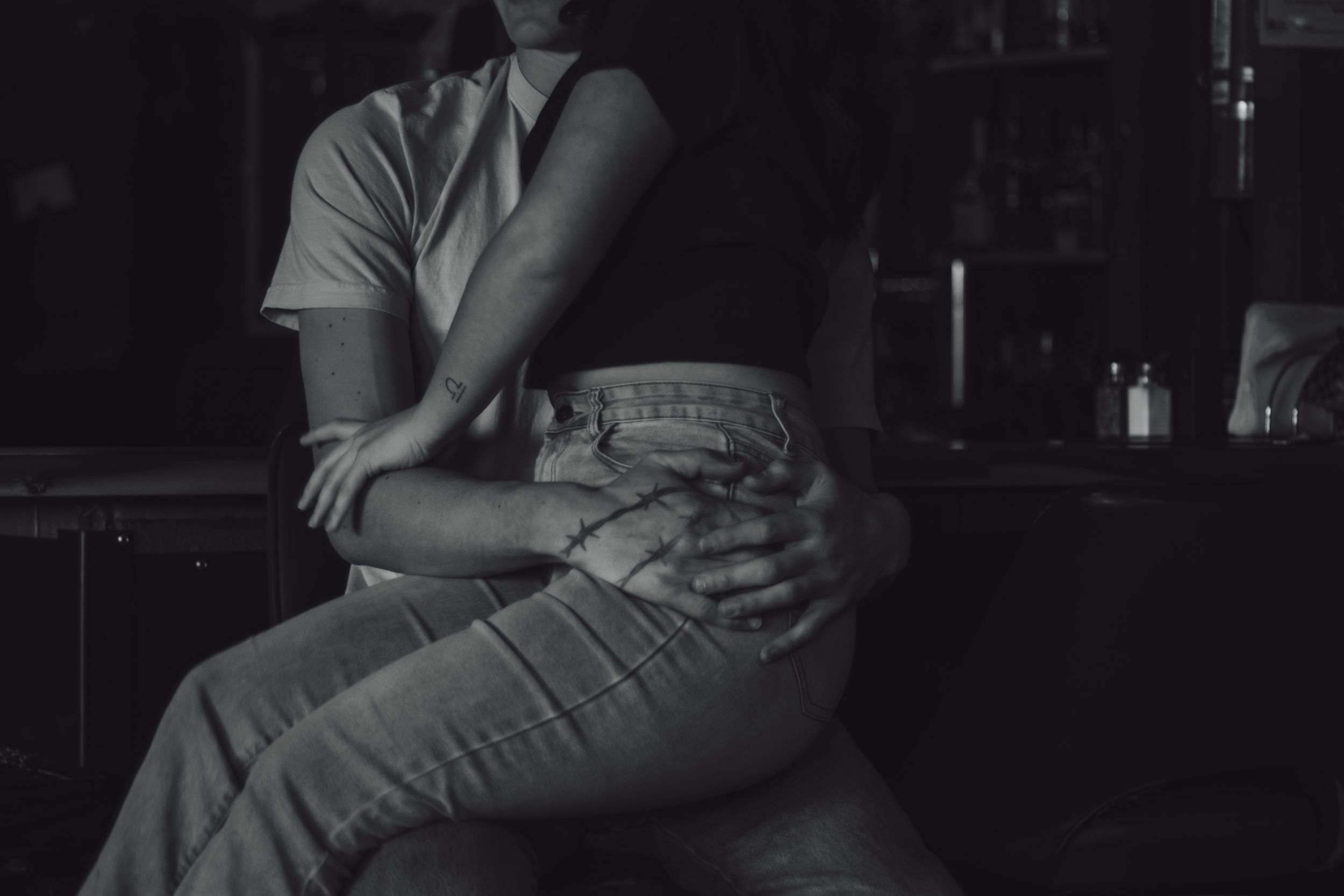 Black and white photo of a couple sitting closely together at Tommy's Tavern, a dimly lit dive bar in Yelm WA captured by local photographer