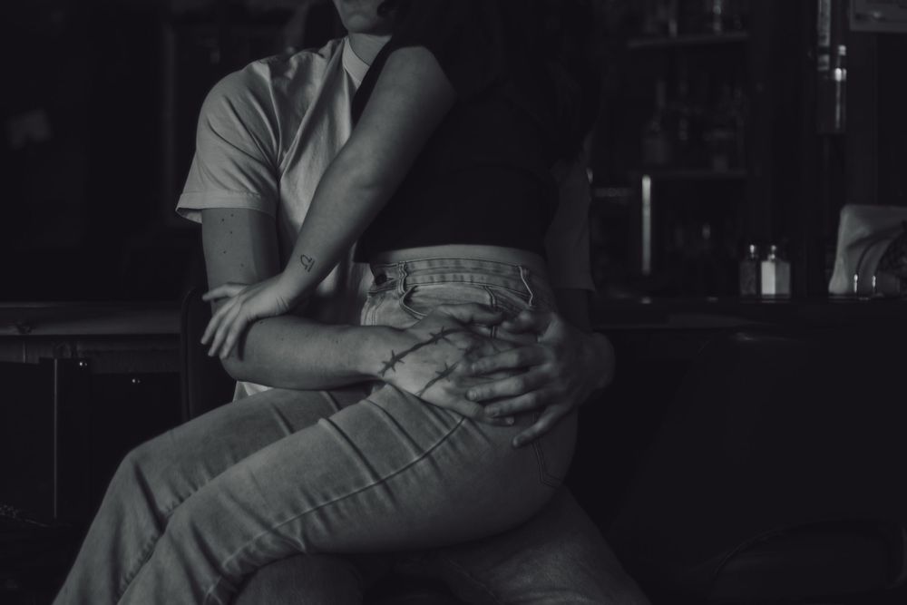 Black and white photo of a couple sitting closely together at Tommy's Tavern, a dimly lit dive bar in Yelm WA captured by local photographer