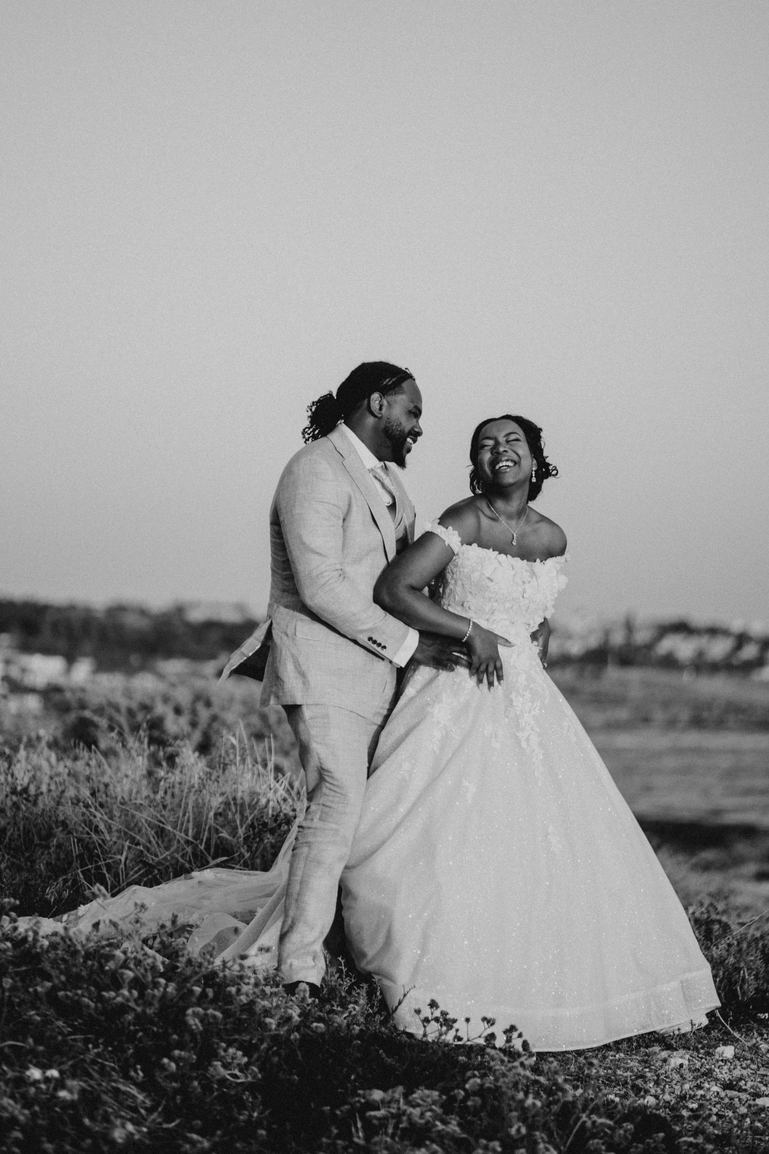 A romantic wedding moment captured among lush greenery with two people embracing in formal attire.