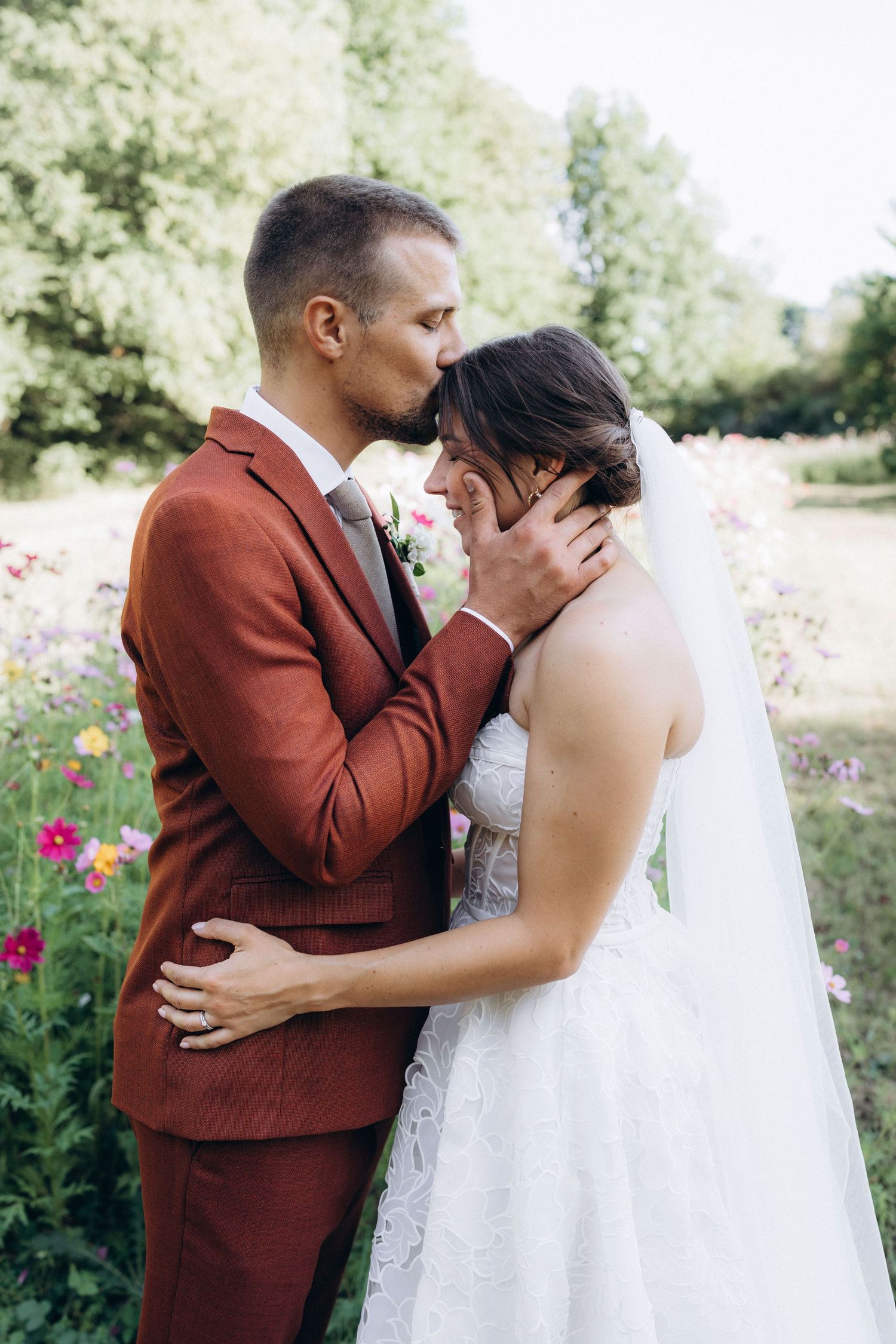 A romantic moment captured between newlyweds in a garden with pink flowers during their first look wedding photos.