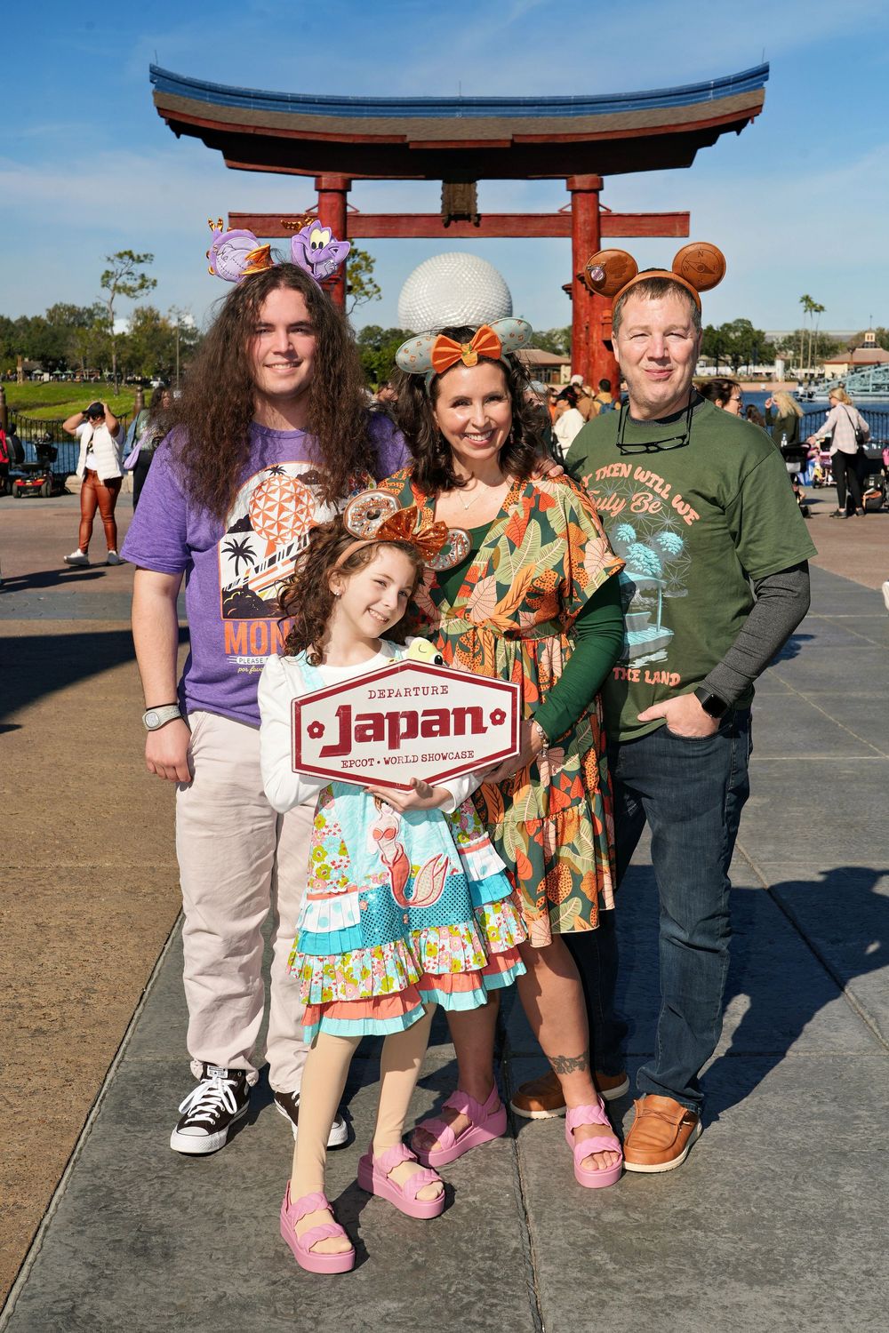 Group poses together at Disney World's EPCOT Japan pavilion with traditional torii gate and themed decor in background.