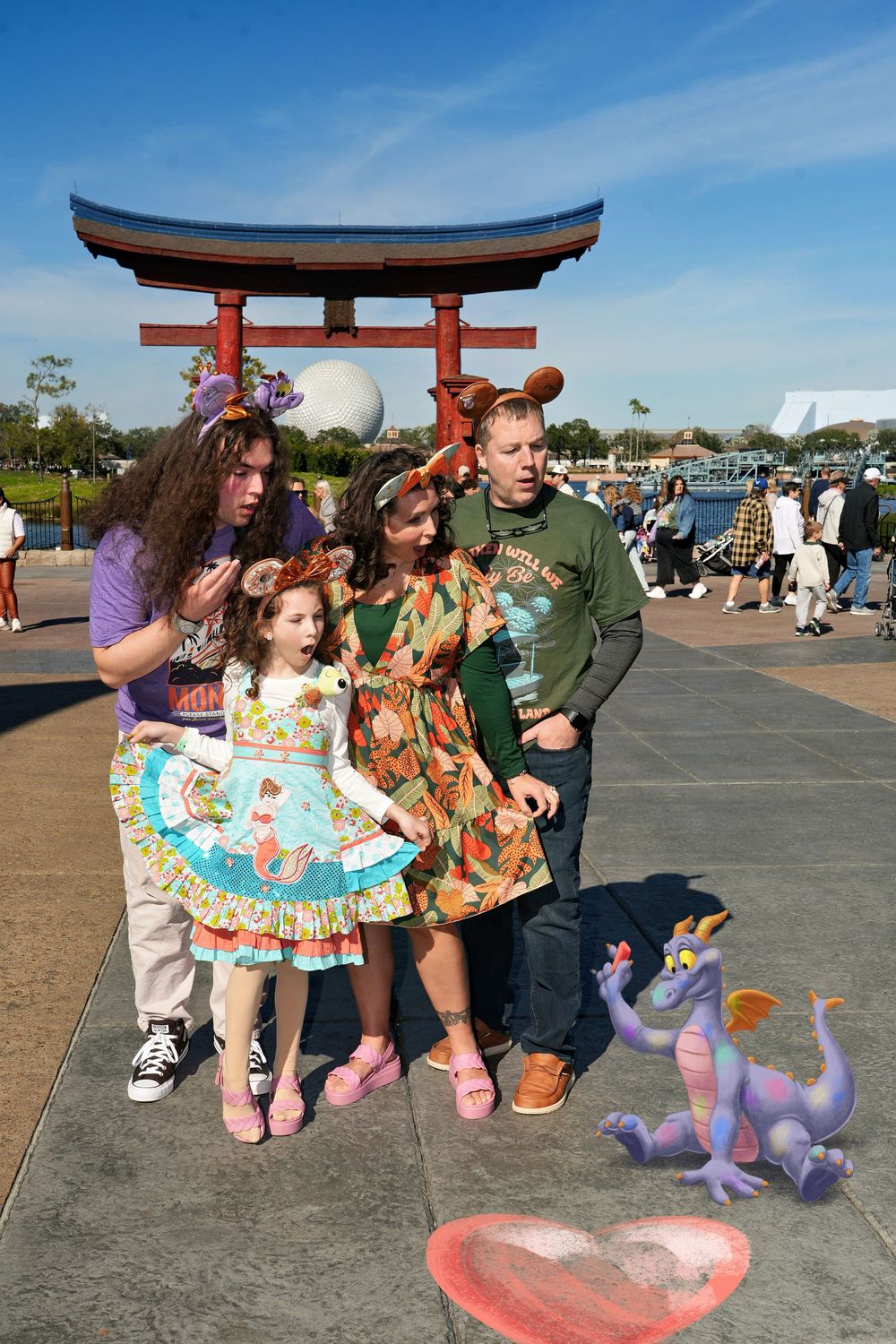 Group of people pose with colorful dragon figures near a Japanese torii gate at an outdoor festival.