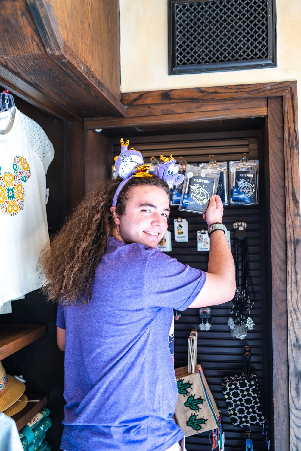 Person in purple t-shirt decorating a wall with decals and artwork in a home interior space.