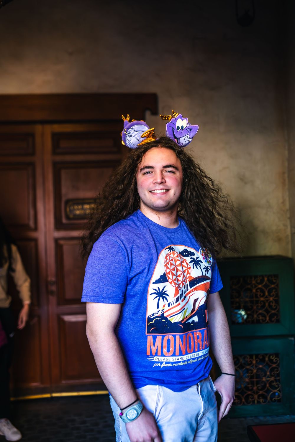 Person wearing a blue t-shirt and light pants poses with a flower crown filter against a dark background.