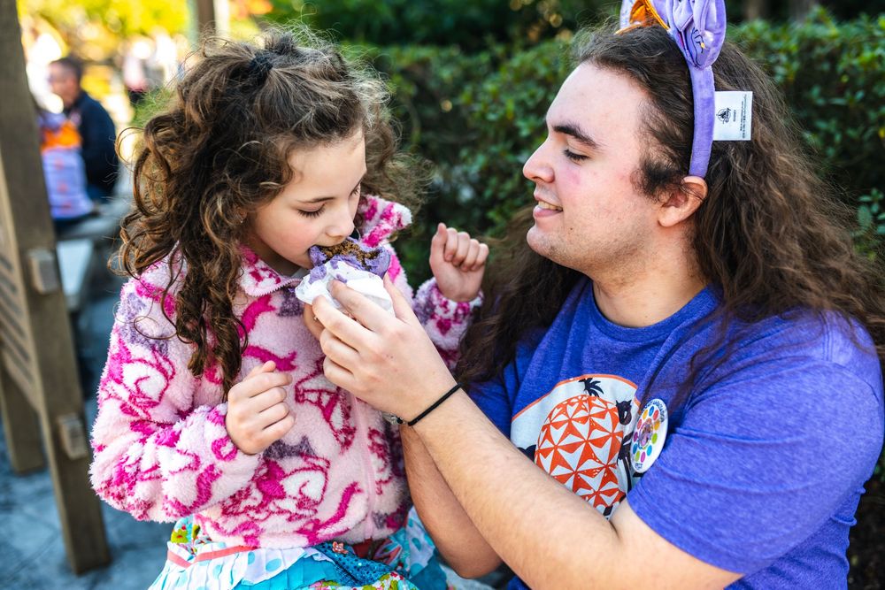 Two people share a sweet moment while enjoying ice cream together in an outdoor setting.