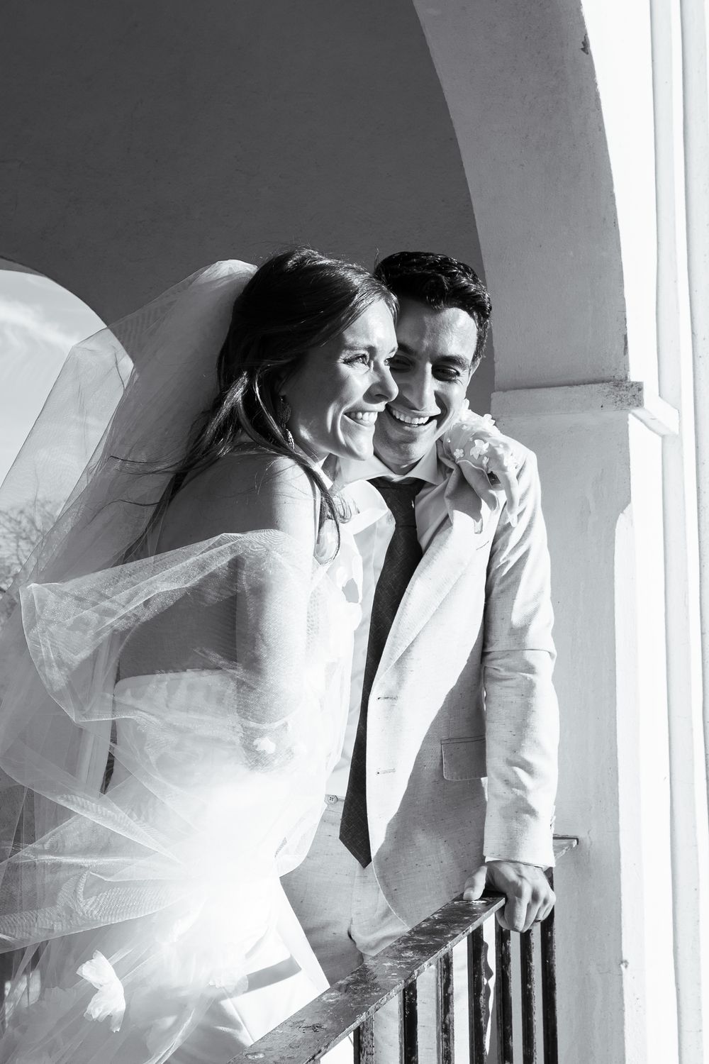Black and white wedding photos showing romantic moments between newlyweds under elegant archways.