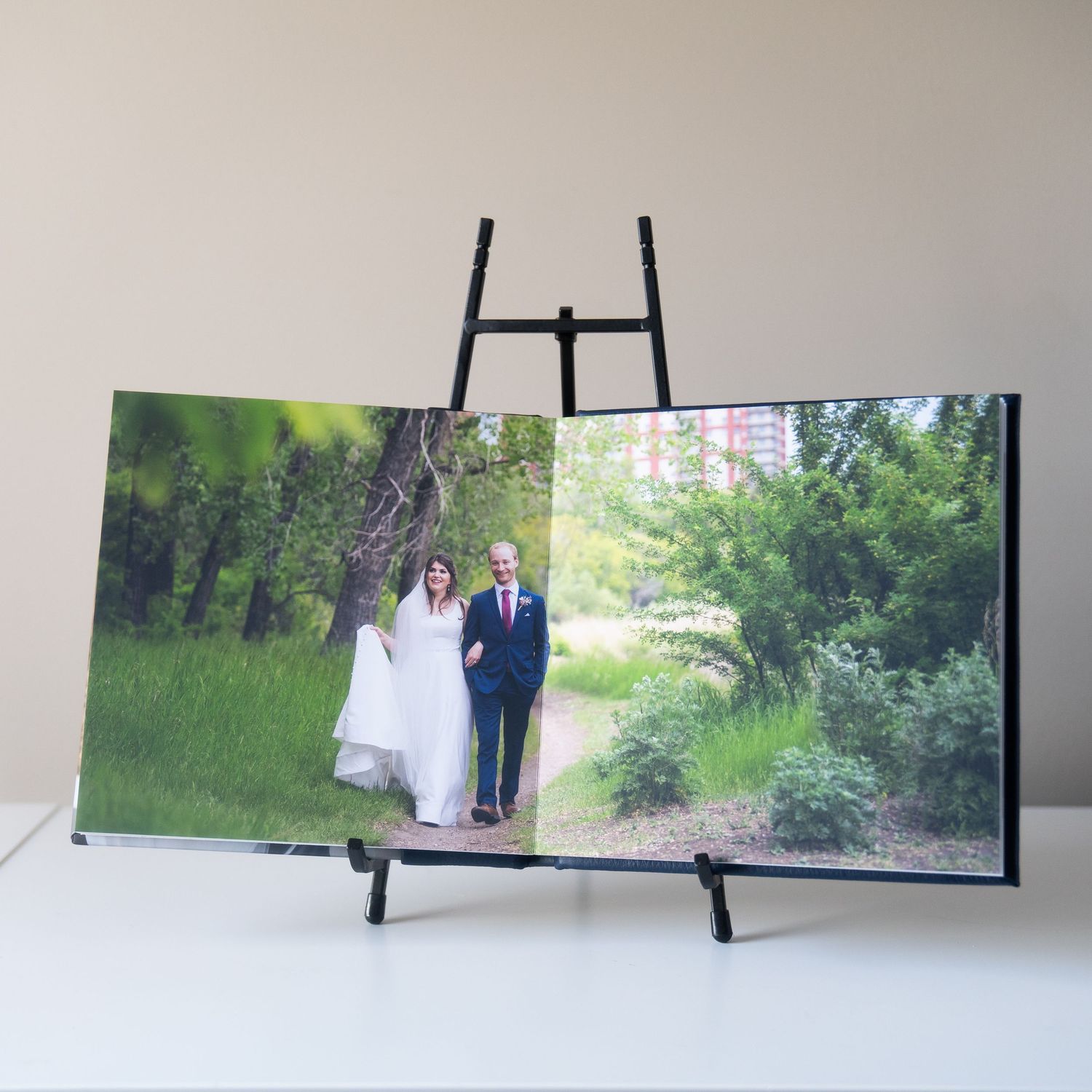 An open album spread showing an image of a wedding couple walking together through a lush green outdoor setting,