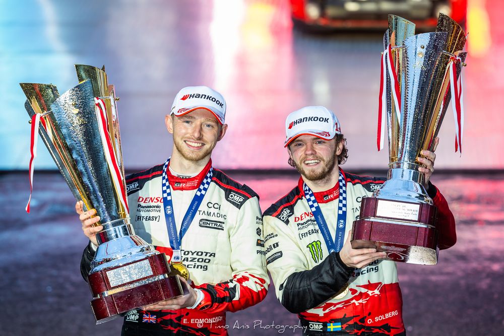 Racing trophies and awards displayed on illuminated podium with red and blue lighting effects.