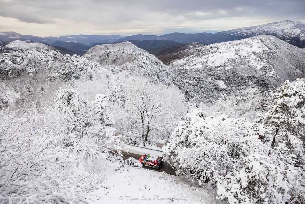 Snow-covered mountain peaks stretch across a rugged winter landscape under cloudy skies.