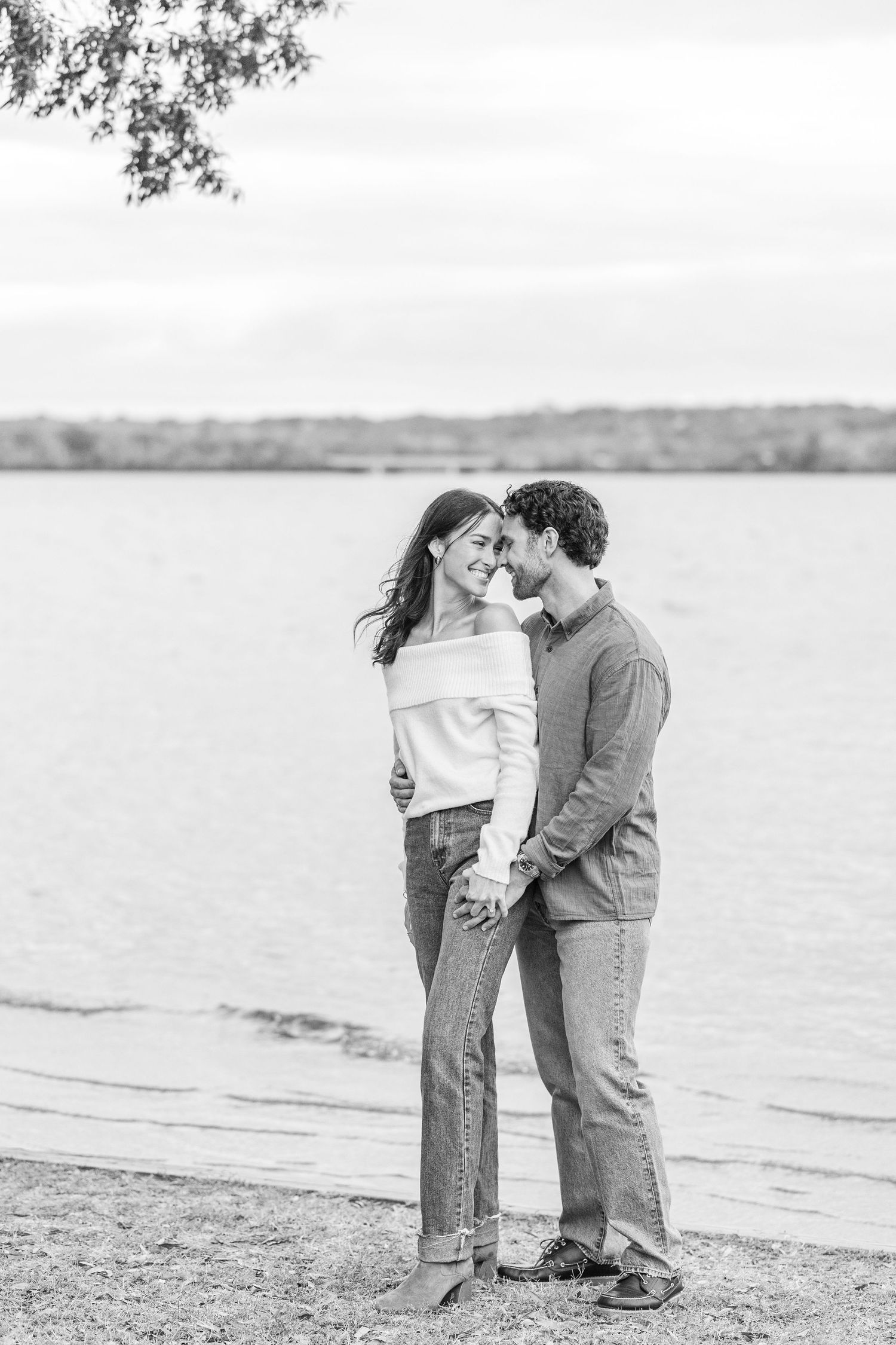 A romantic couple embraces on a serene beach shoreline in a series of black and white photographs.