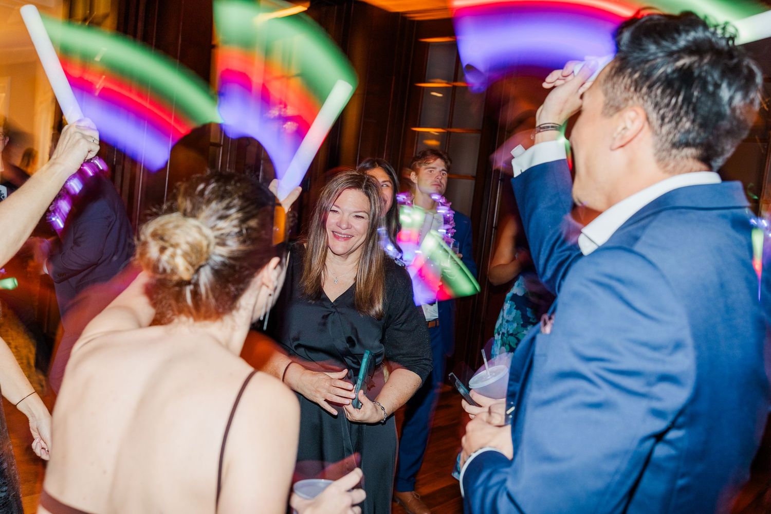 People dancing and celebrating at a lively party with colorful lighting and festive atmosphere.